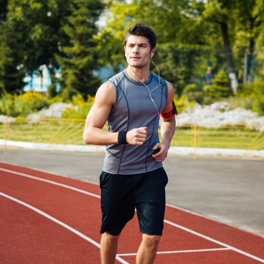 Man running on a track with trees and flowers in the background