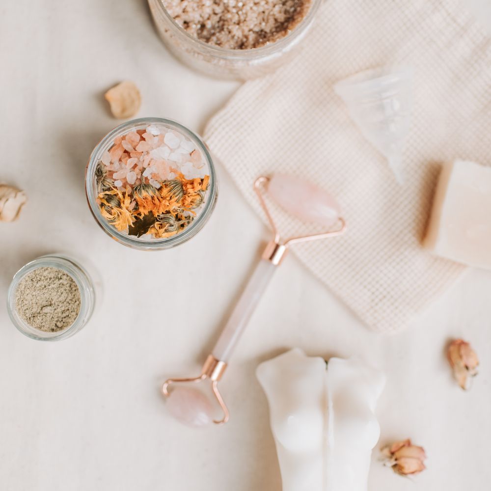 Skincare tools and products on a light surface with a focus on a rose gold roller.
