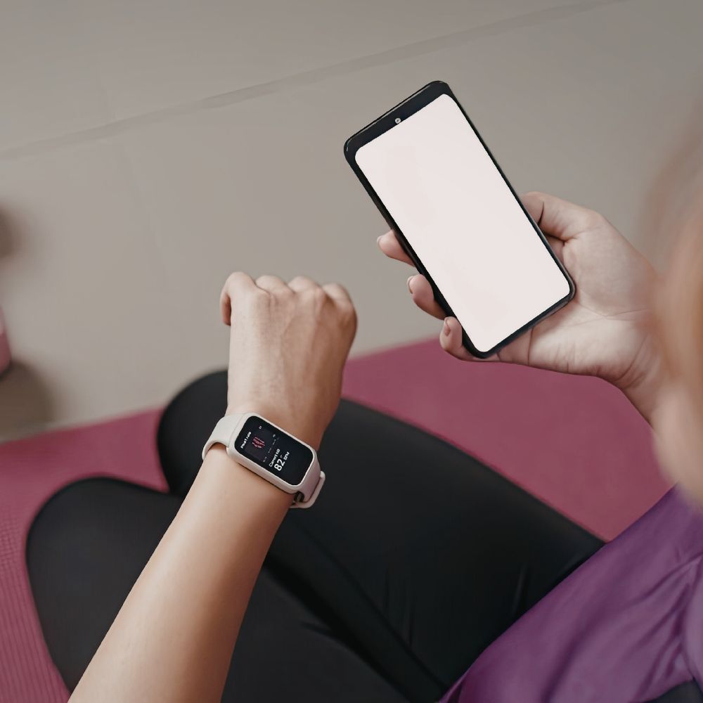 Person using a smartphone and smartwatch on a pink mat