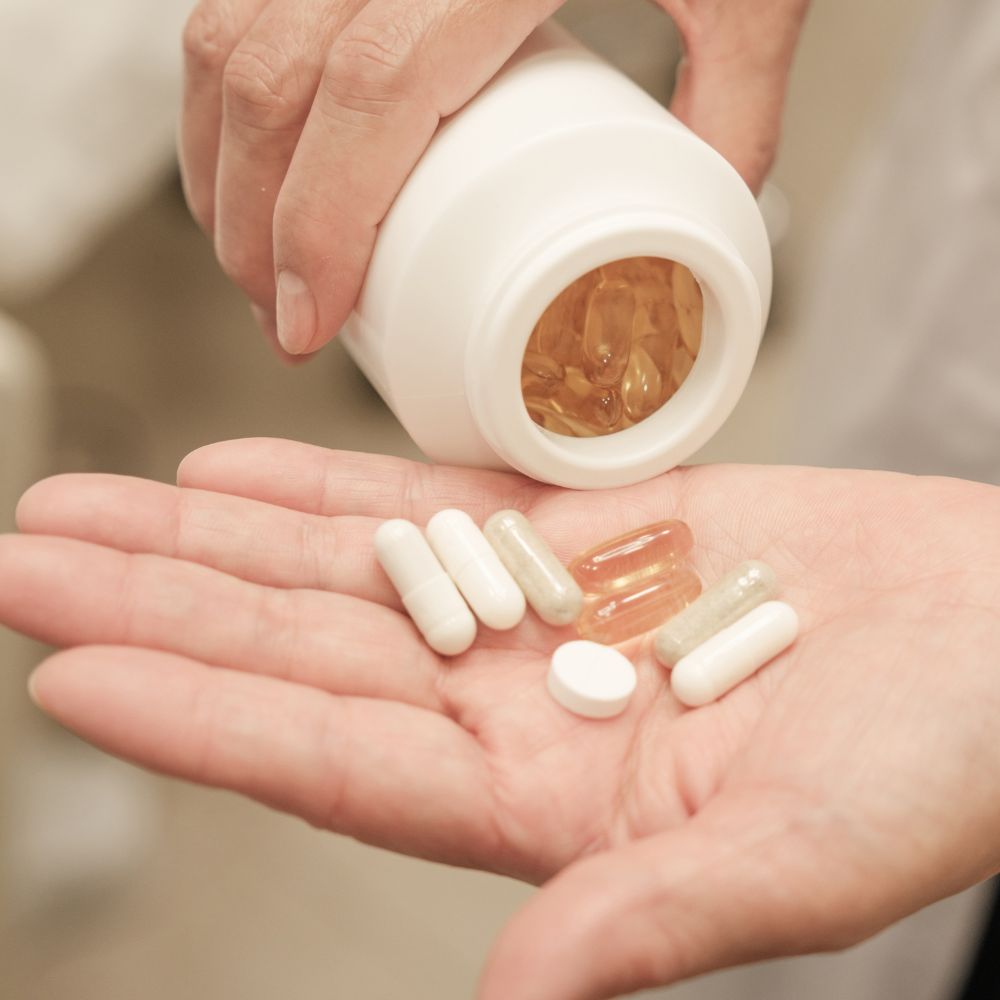 Person holding a bottle of supplements with pills in their hand