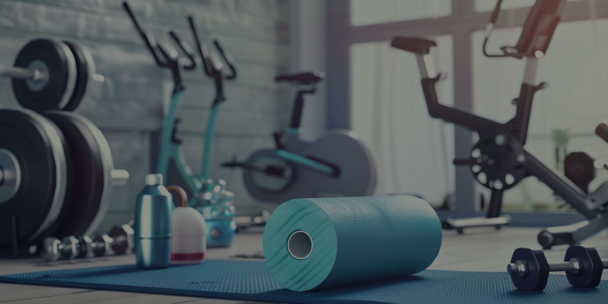 Gym equipment including weights, a bike, and a foam roller on a mat.