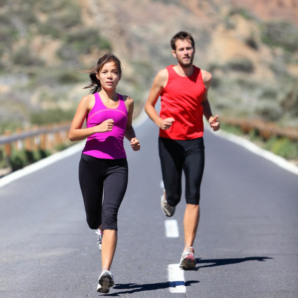 Two people running on a road with a scenic background