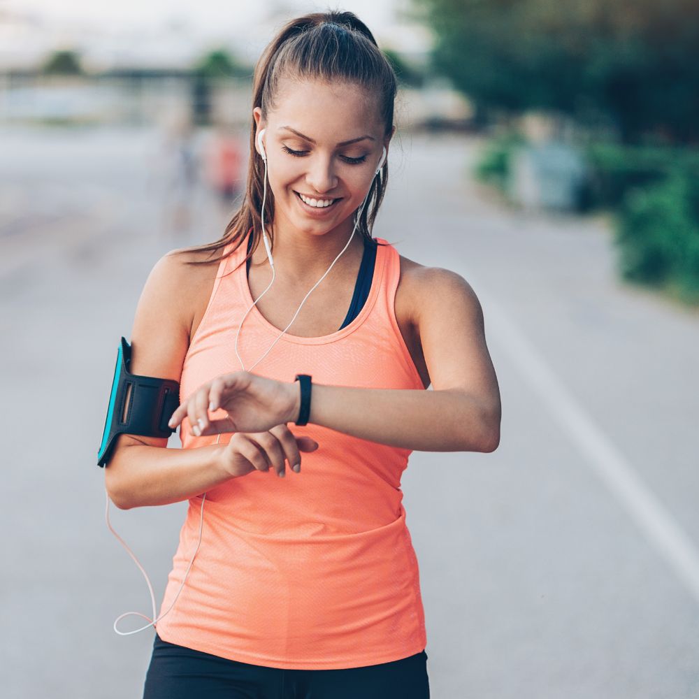 Woman in athletic wear checking her watch outdoors